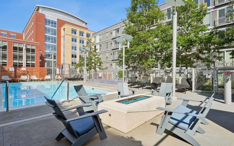a fire pit with chairs in front of a pool